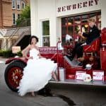 A newly married couple rides away on the old red firetruck