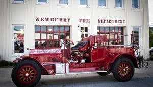 The old red firetruck sits in front of the historic Newberry Firehouse
