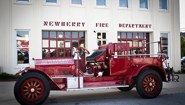 The old red firetruck sits in front of the historic Newberry Firehouse