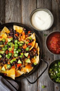 Classic Nachos with Tortilla chips melted cheese sauce jalapeno peppers avocado salsa and sour cream