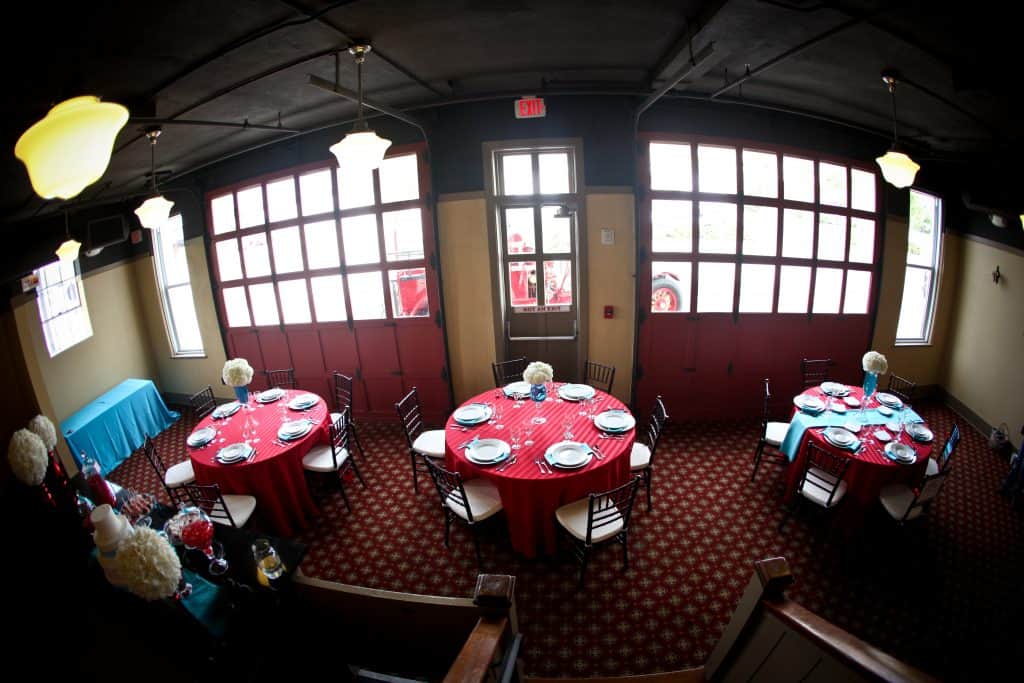 The interior of the Newberry Firehouse with three tables set with full place settings for a wedding