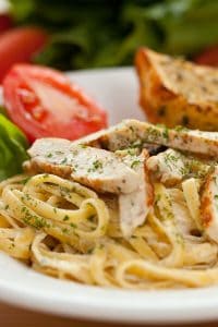 Chicken-topped Fettuccine Alfreda on a white plate