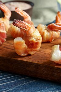 bacon-wrapped shrimp on a wooden serving tray